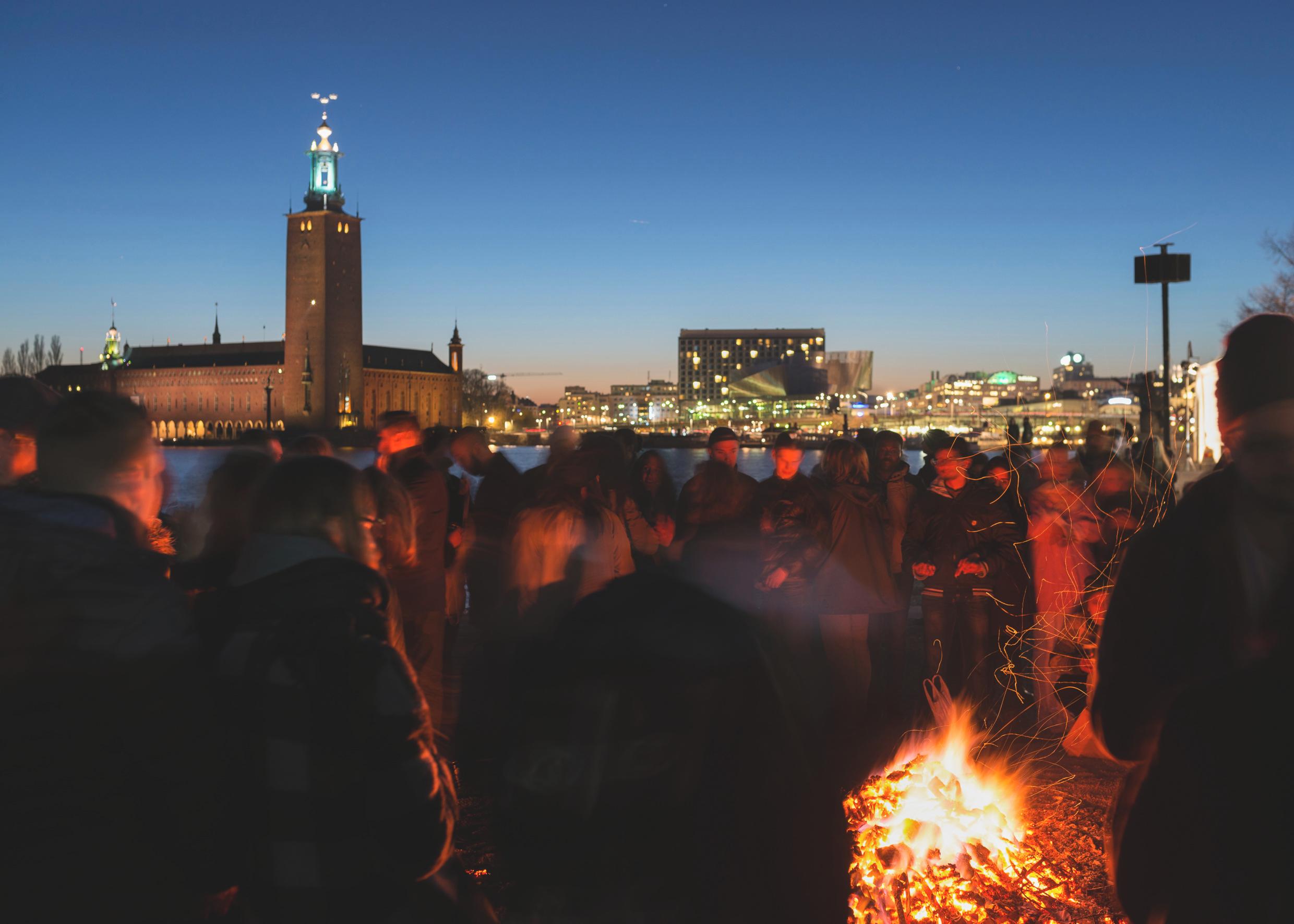 حشود من الناس تقف في الظلام وهم ينظرون إلى نار مشتعلة.