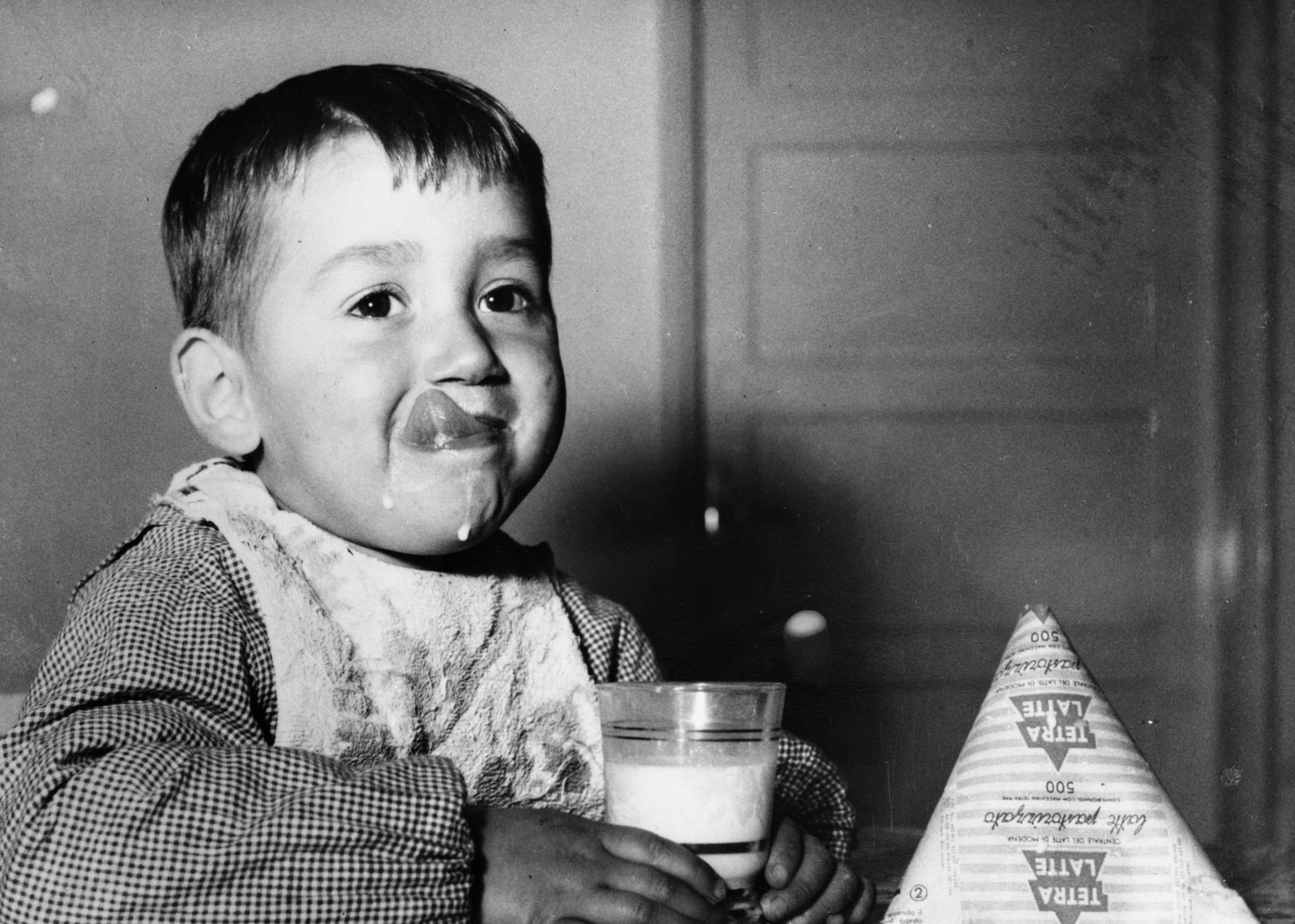 طفل إيطالي يحمل كوبًا من الحليب وبجانبه عبوة من نوع «تيترا باك».